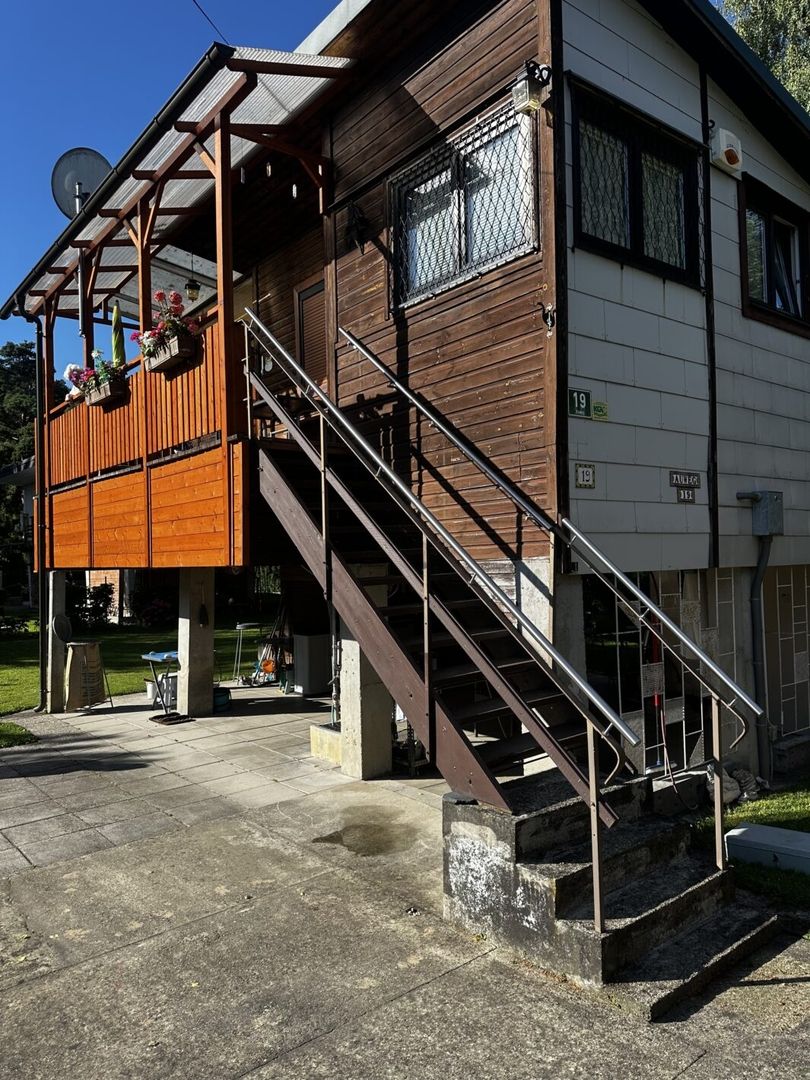 Eine dunkelbraune Mittelholmtreppe an einem älteren Holzhaus