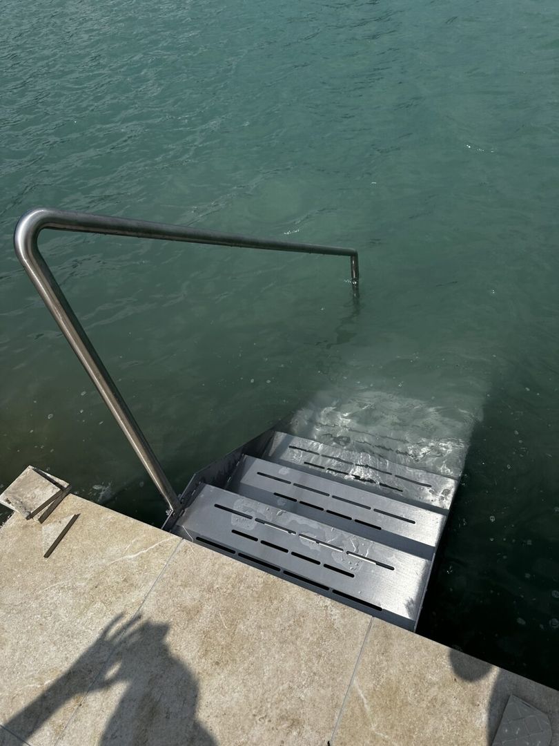 Eine Edelstahltreppe die in einen See führt von hinten fotografiert