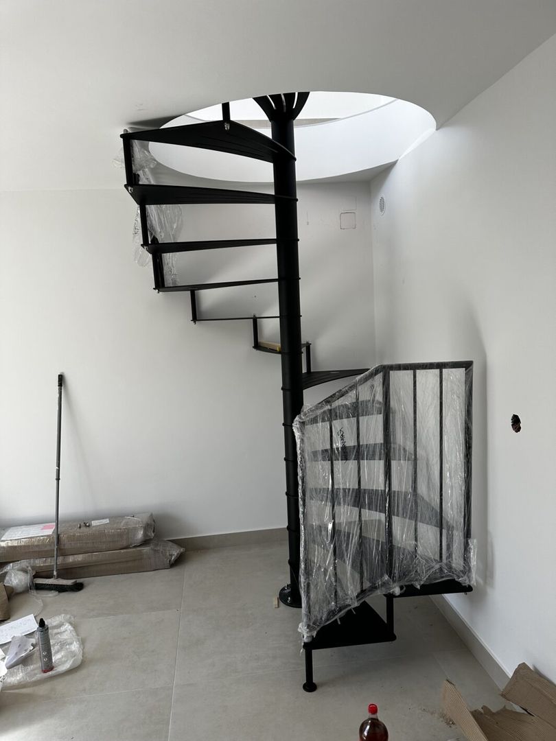 Aufbau einer schwarzen Spindeltreppe aus Metall mit schwarzem Geländer in einem hellen Raum