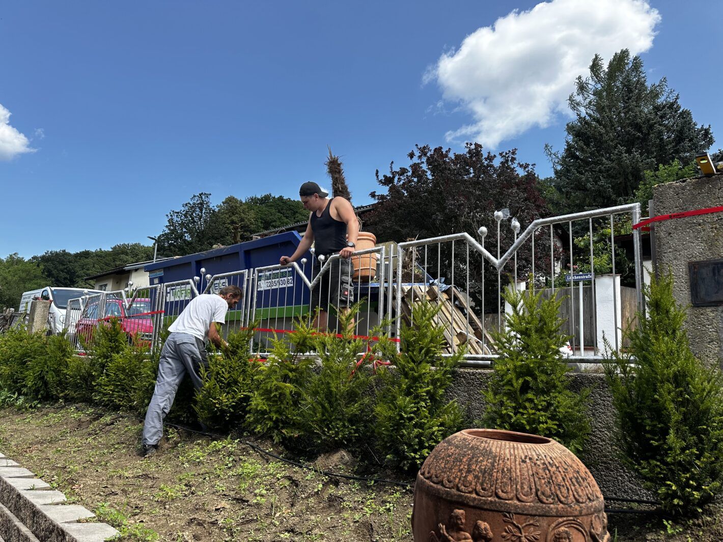 Zwei Arbeiter bauen einen Edelstahl Zaun an einem Garten auf