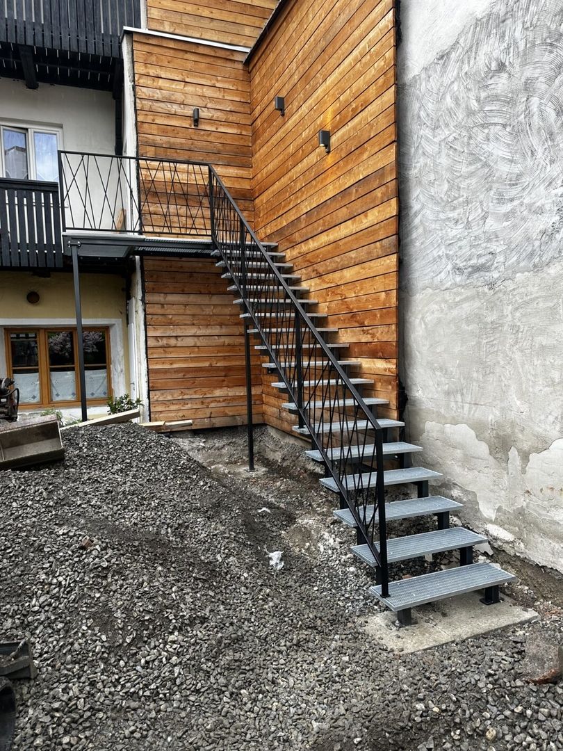 Eine Zweiholmtreppe aus Metall mit Metallgeländer steht an einer Holzhauswand
