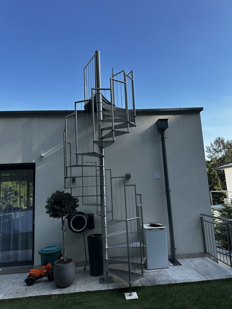 Eine Edelstahl Spindeltreppe an einer weißen Hauswand