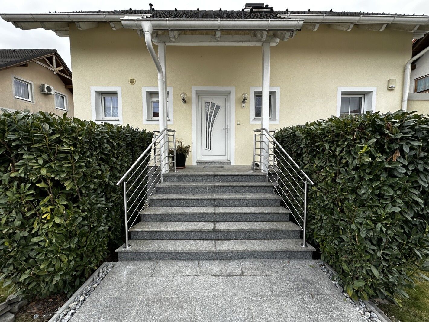 Ein Edelstahlgeländer an einer Steintreppe vor einem Haus