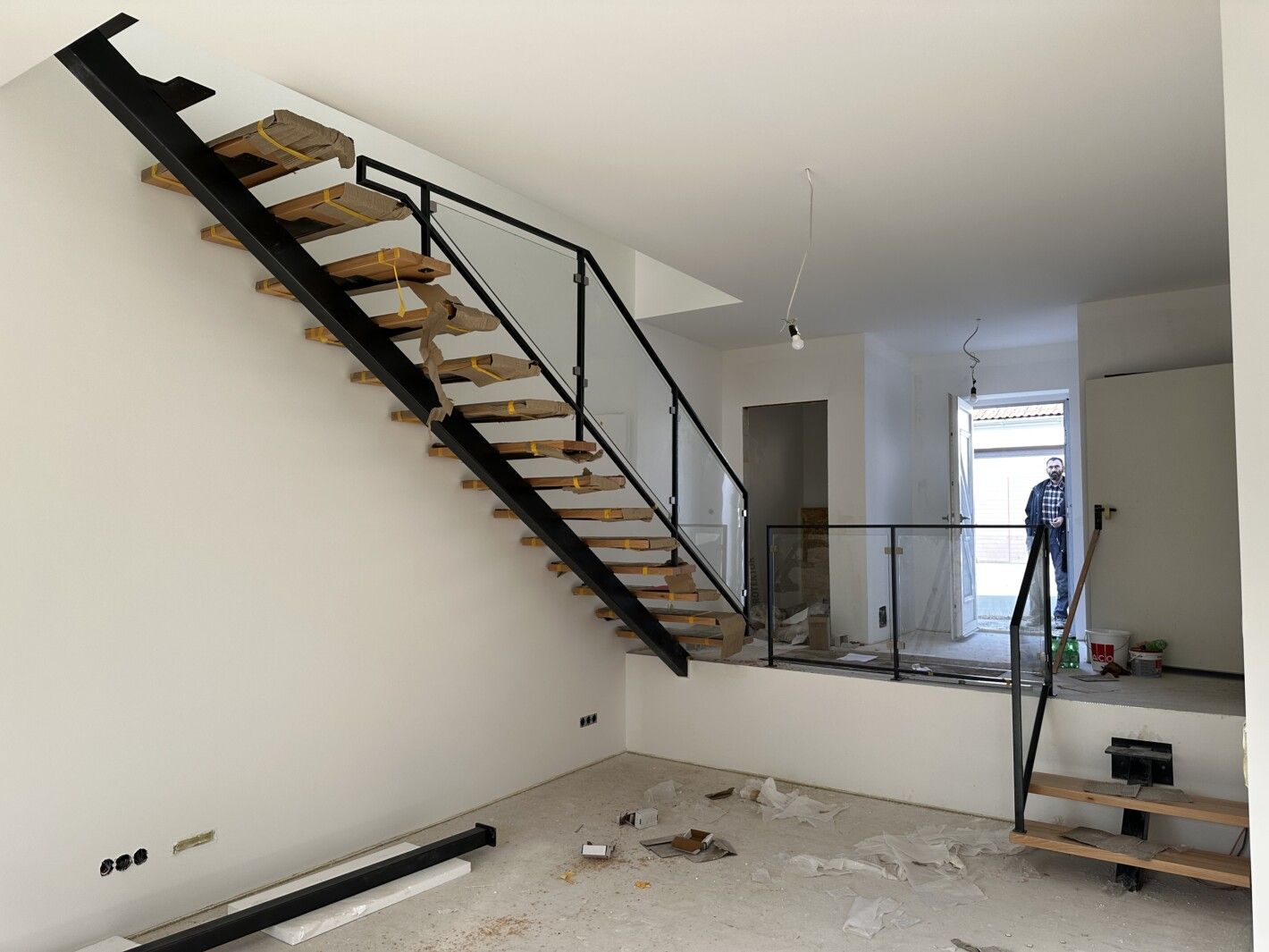 Eine Mittelholmtreppe aus Holz mit schwarzem Stahlgeländer in einem hellen Raum