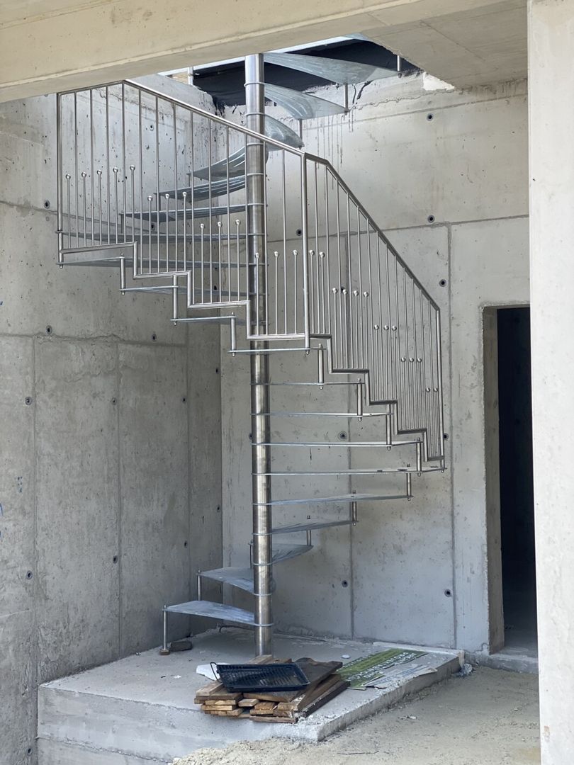 Eine Edelstahl Spindeltreppe  in einem hellen Raum mit Betonwänden