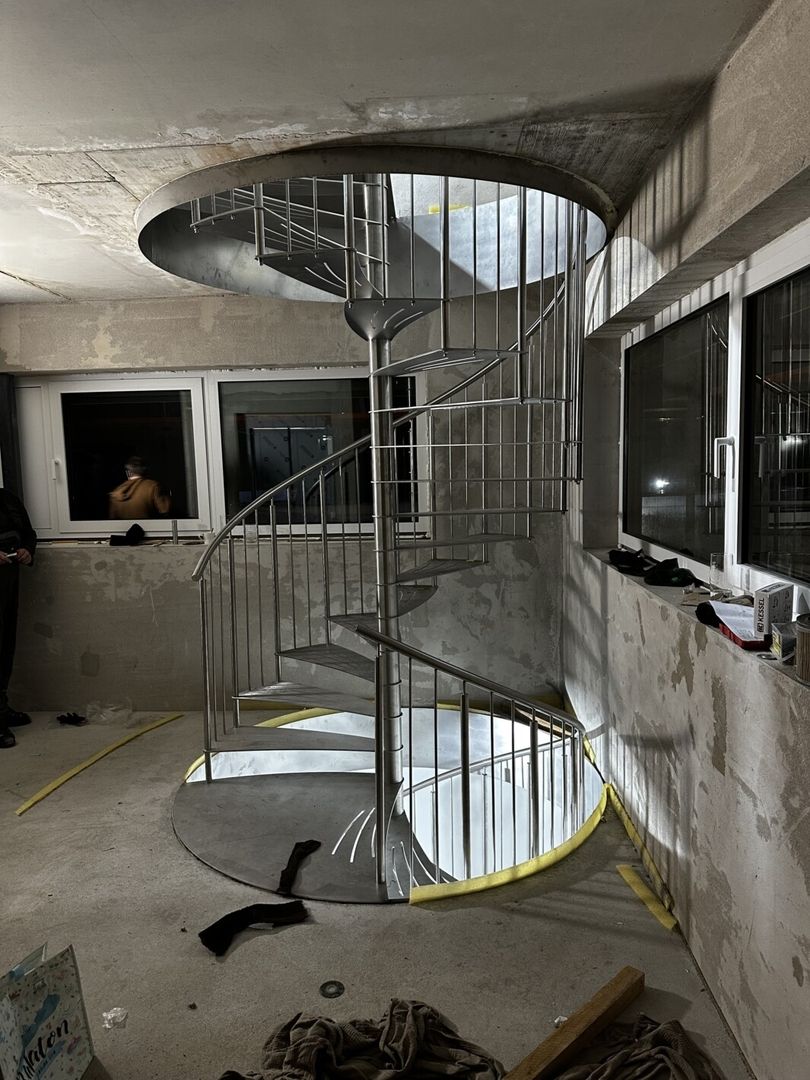 Eine Spindeltreppe aus Metall mit Metallgeländer in einem Zimmer mit Betonwänden