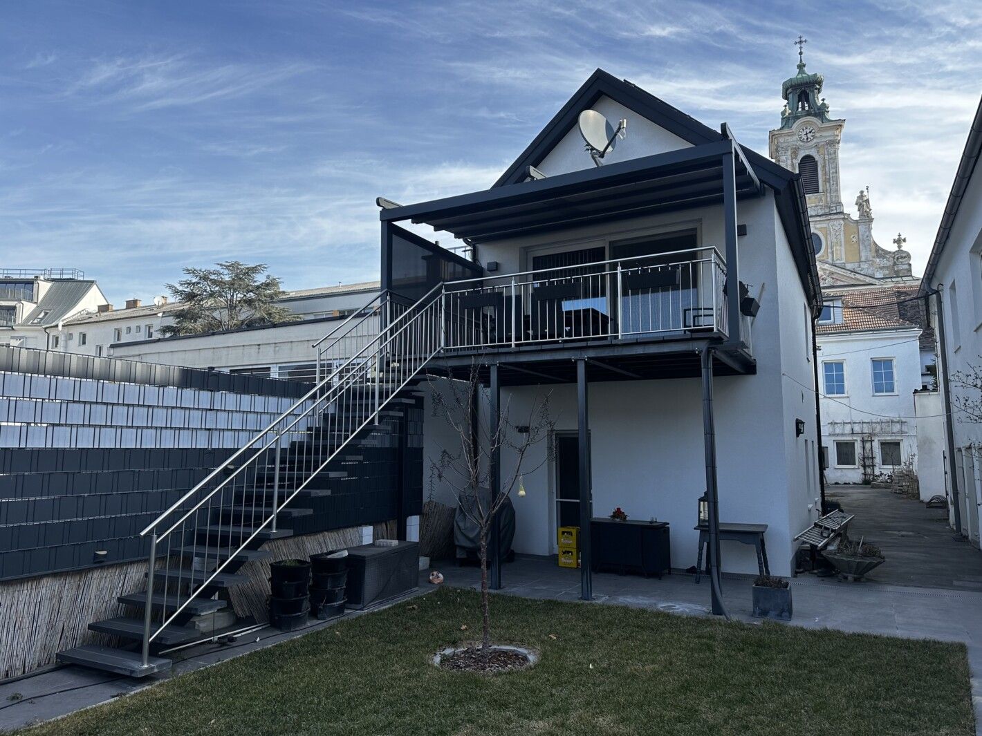 Eine Mittelholmtreppe die zu einem Balkon an einen weißen Haus führt
