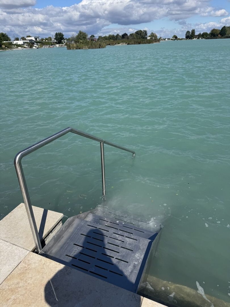 Eine Edelstahltreppe die in einen See führt von hinten fotografiert