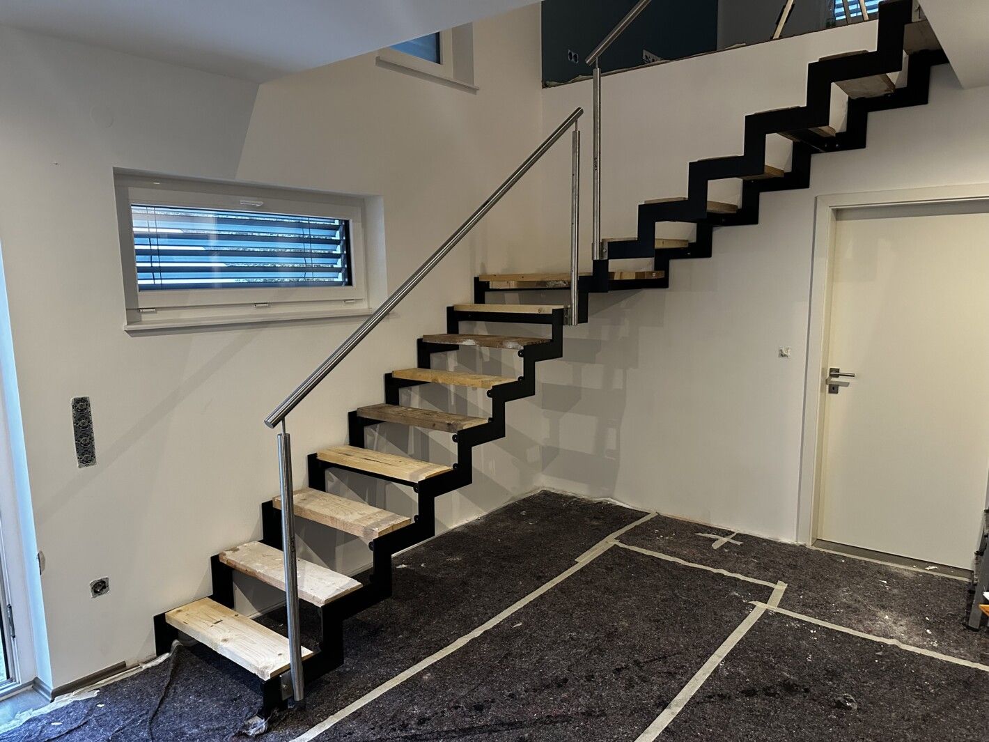 Eine Stahlwangentreppe mit Eckpodest und Holztreppen in einem hellen Raum