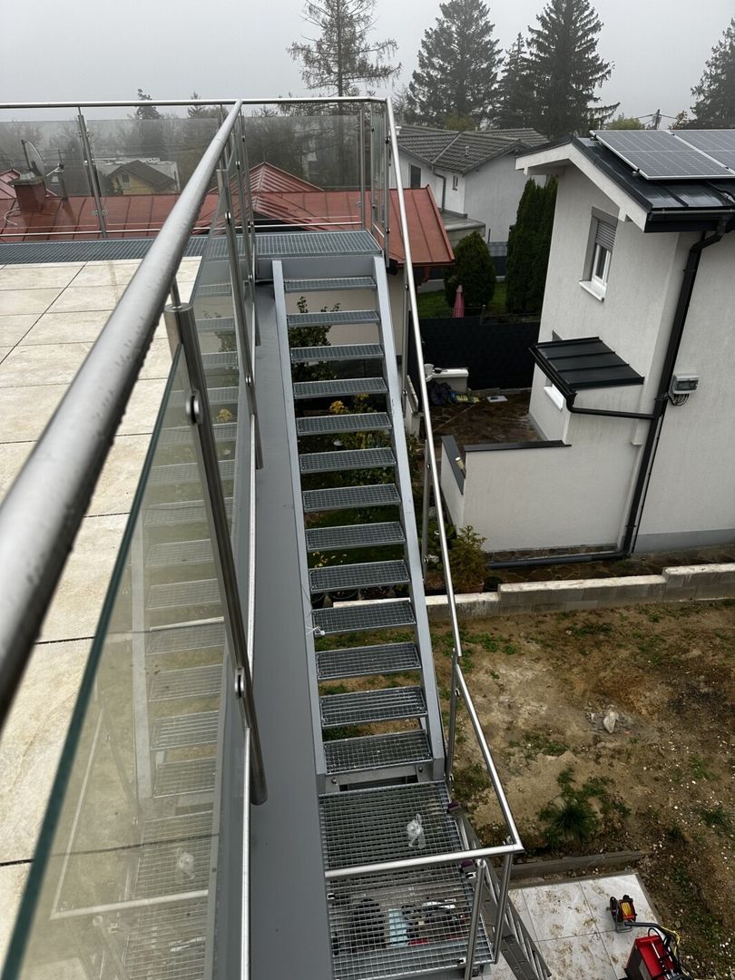 Ein Edelstahl Glasgeländer an einer Treppe die zu einer Dachterrasse führt