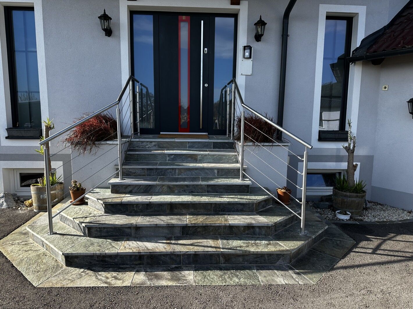 Ein Edelstahl Seilgeländer an einer Steintreppe zu einer Eingangstür