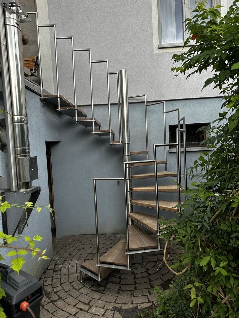 Eine Spindeltreppe aus Bangkirai mit Edelstahlgeländer, die zu einem Balkon führt