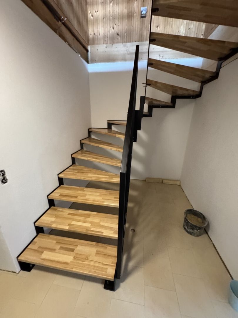 Eine Stahlwangentreppe aus Holz und Metallgeländer in einem hellen Flur