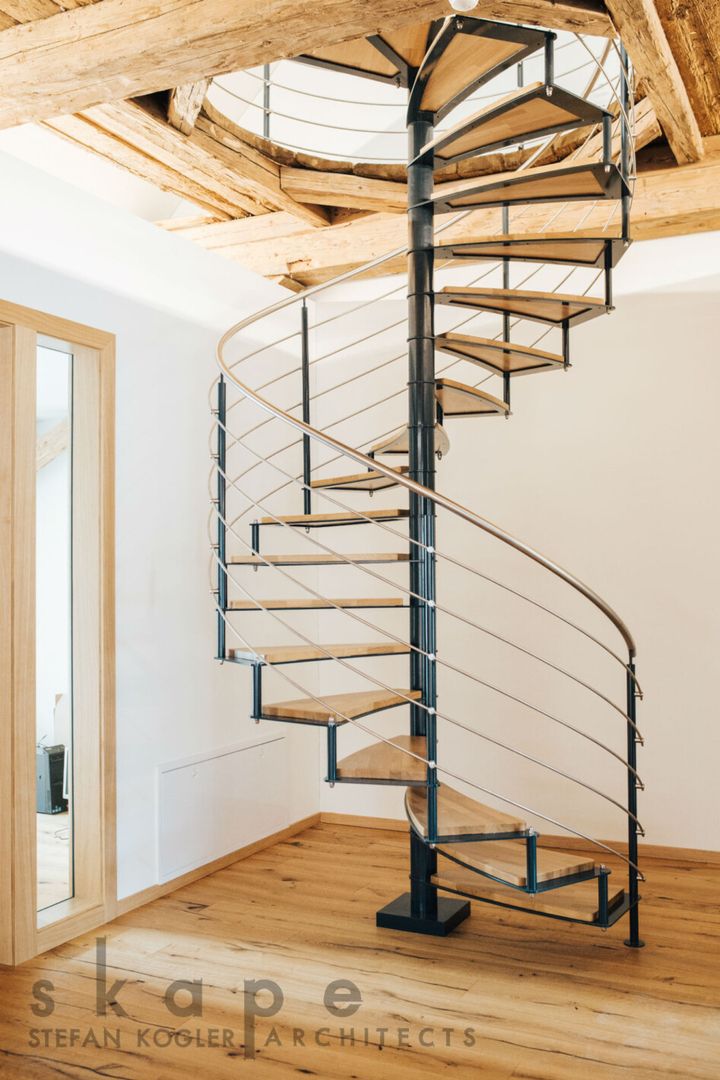 Eine Spindeltreppte aus Holz mit Metallgeländer in einem hellen Raum