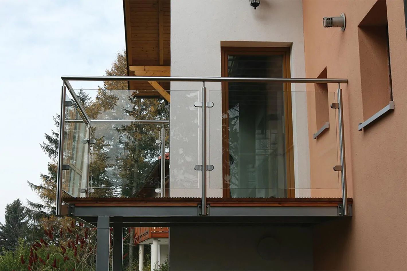 Ein Glasbalkon mit einem Metallgeländer und einer Tür, die den Zugang zum Innenraum ermöglicht.