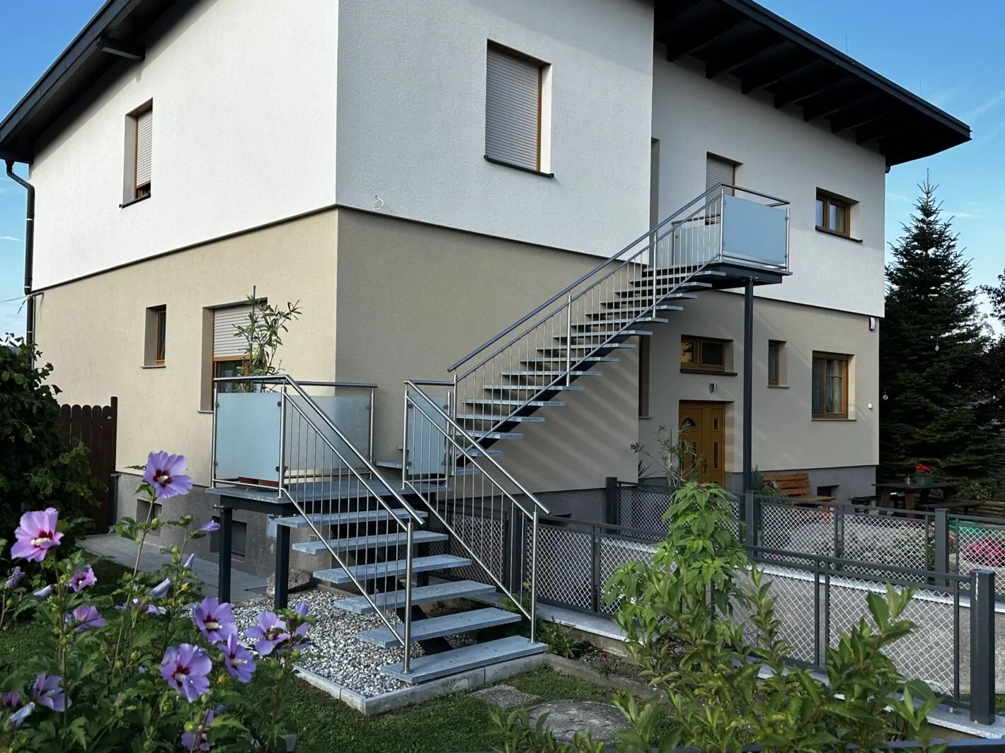 Mittelholmtreppen aus Stein mit silbernem Geländer an einer Hauswand
