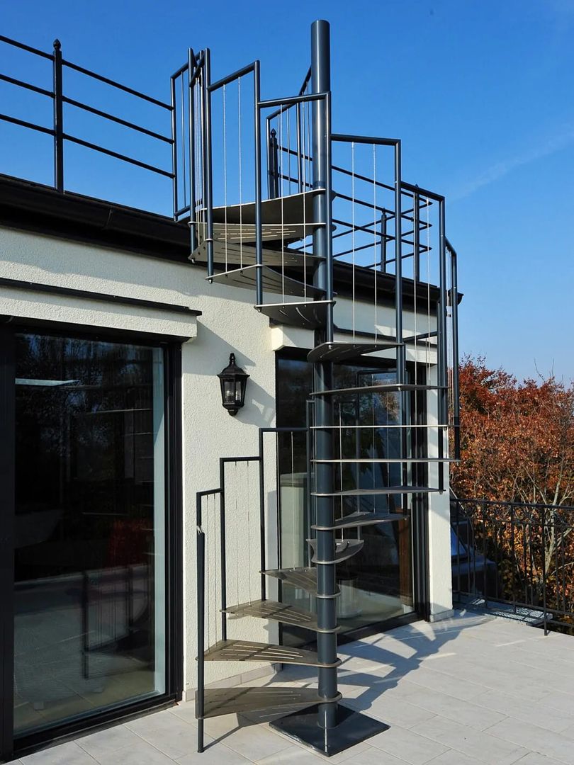 Schwarze Spindeltreppe aus Metall mit schwarzem Geländer, auf einem Balkon, zum Dach