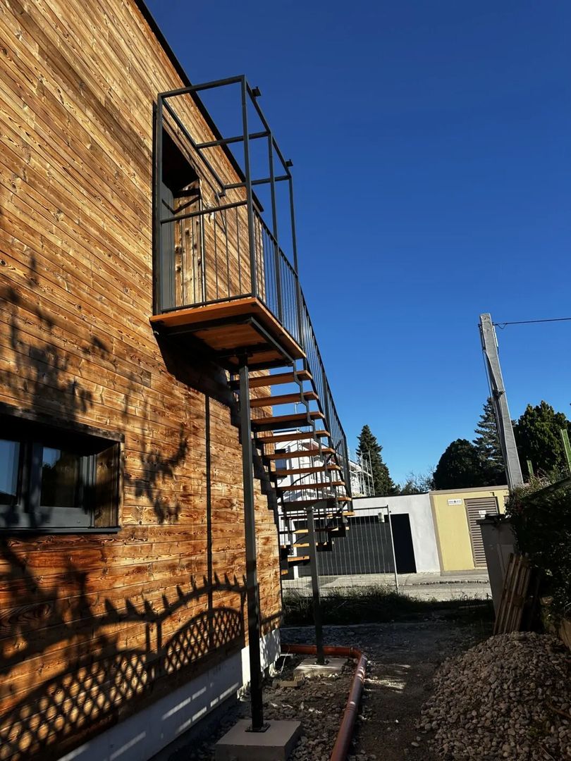 Stahlwangentreppe aus Holz und Metallgeländer, an einer Hauswand um eine Ecke