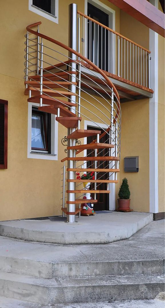 Spindeltreppe aus Holz mit Metallgeländer, an einem gelben Haus