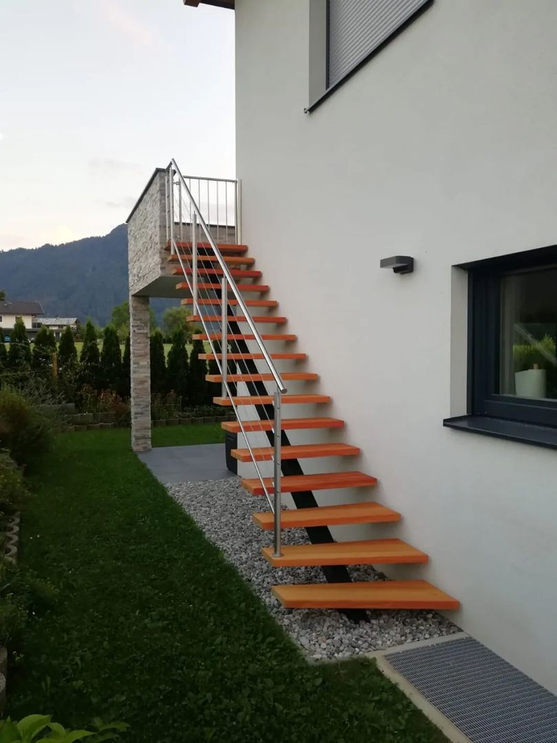 Mittelholmtreppen aus Holz mit Metall Geländer an einer Hauswand