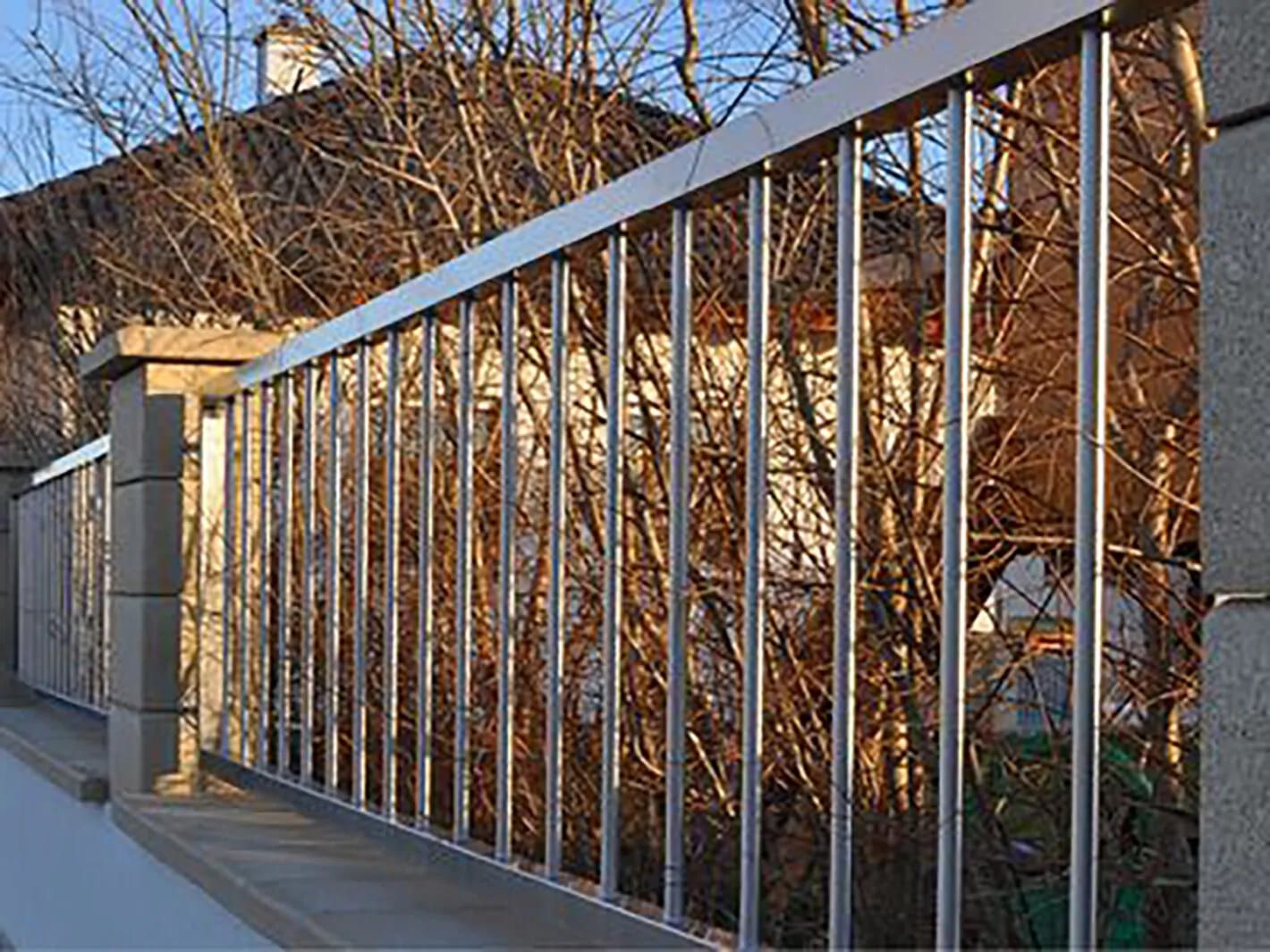 Edelstahl Zaun vor einigen Bäumen