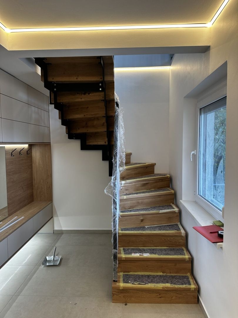 Fertigstellung einer Stahlwangentreppe aus Holz und Metallgeländer in einem hellen Flur