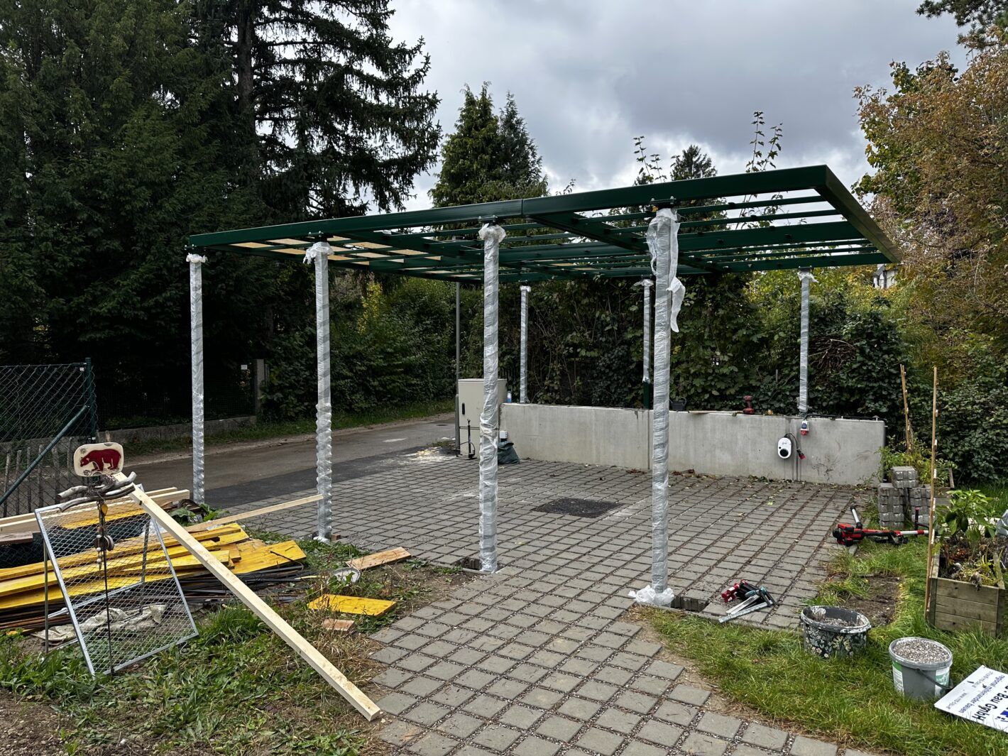 Aufbau eines Carports in moosgrün vor einigen Bäumen