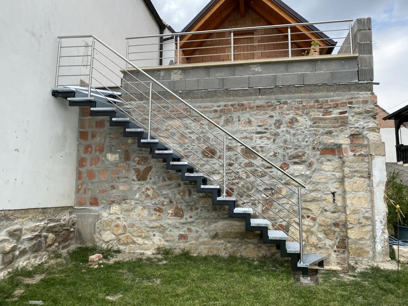 Zweiholmtreppe aus Metall mit Metallgeländer, an einer Steinwand